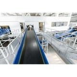 Trough bed belt conveyor in warehouse setting for industrial bulk material handling operations
